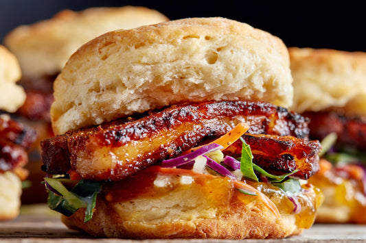 Pork Belly Slider on a biscuit with caramelized sliced pork and an Asian coleslaw
