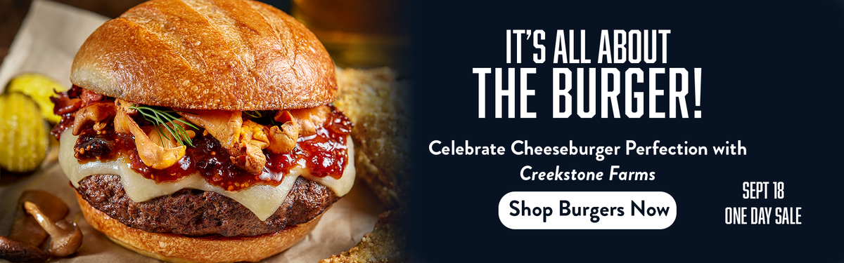 Promotional banner for Creekstone Farms featuring a close-up of a gourmet cheeseburger with bacon, cheese, and sauce on the left, and large white text on a dark background on the right reading 'IT'S ALL ABOUT THE BURGER!' and 'Shop Burgers Now'.